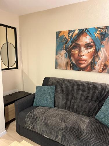 a living room with a couch and a painting on the wall at Studio cosy rénové climatisé avec piscine proche de toutes commodités in Fréjus