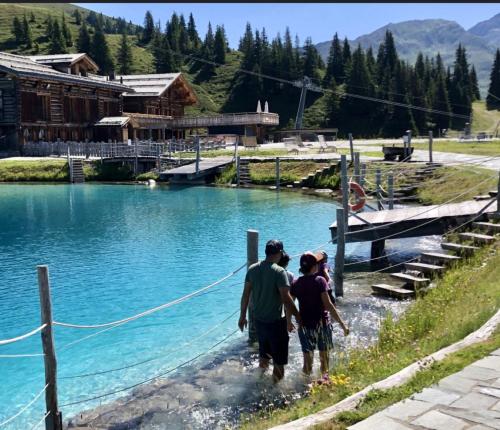 two people walking in the water near a lake at Chalet apartment & mountain view in Saas