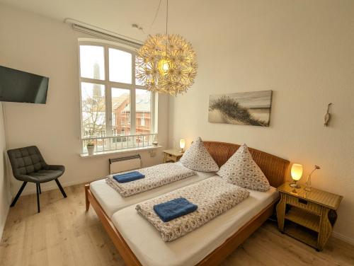 a bedroom with two beds and a chandelier at Ferienwohnung Heimathafen in Borkum