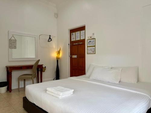 a bedroom with a white bed with a desk and a door at Ardour Lodge "B" Wing in George Town