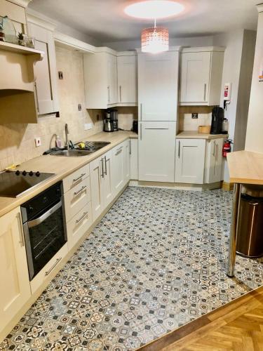 a kitchen with white cabinets and a tile floor at Parkwood House in Dungannon
