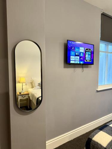 a mirror on a wall with a bed and a television at The Crescent York in York