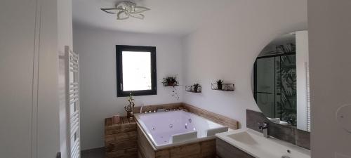 une grande salle de bain avec une baignoire et un lavabo dans l'établissement Villa au calme avec piscine et jacuzzi, à Saint-Vincent-de-Mercuze