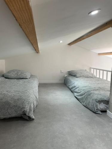 deux lits dans une chambre aux murs blancs dans l'établissement Maisonnette Le Galet Jaune, à Bretignolles-sur-Mer