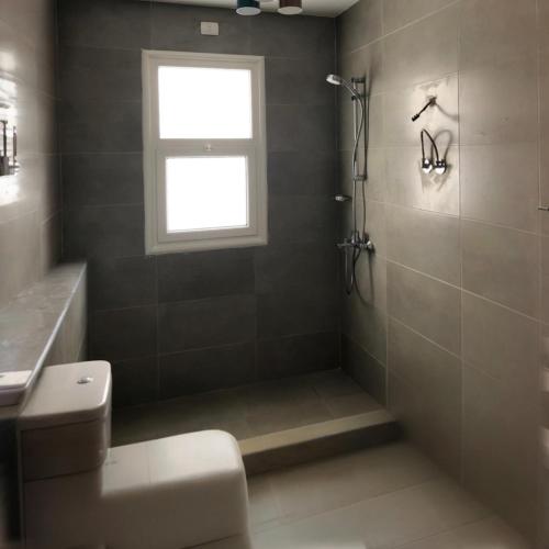 a bathroom with a shower and a toilet and a window at 2BR Amwaj Terrazza & Piscina in Marsa Matruh