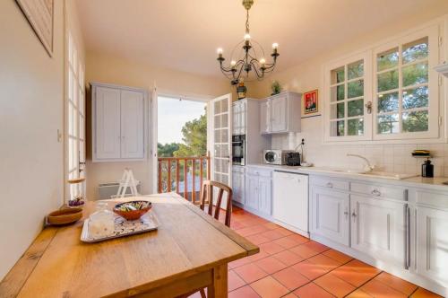 une cuisine avec des armoires blanches et une table en bois dans l'établissement Maison La Pinède authentique & familiale Vue Mer, à Ensuès-la-Redonne