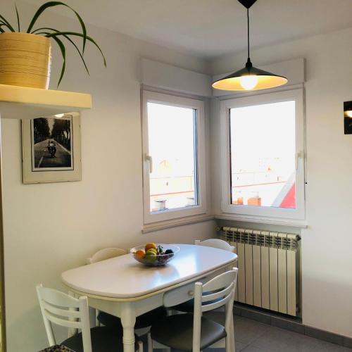 a dining room with a white table and two windows at Piso céntrico y luminoso in León