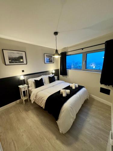 a bedroom with a large bed and two windows at 267 Stylish 2 Bed Apartment City Centre Free Parking in Cardiff