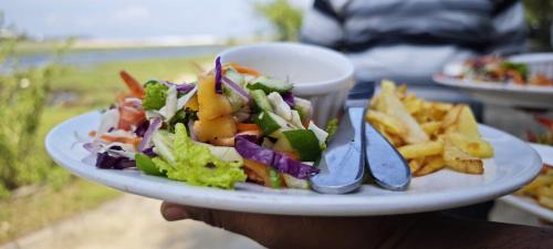 a person holding a plate of salad and french fries at Sunset View Beach Hotel in Arugam Bay