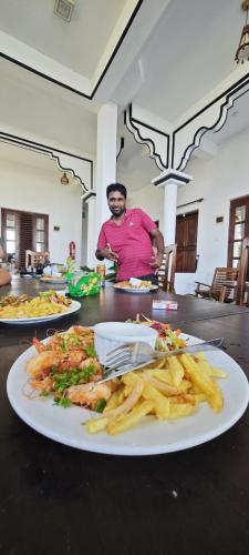 a man sitting at a table with a plate of food at Sunset View Beach Hotel in Arugam Bay