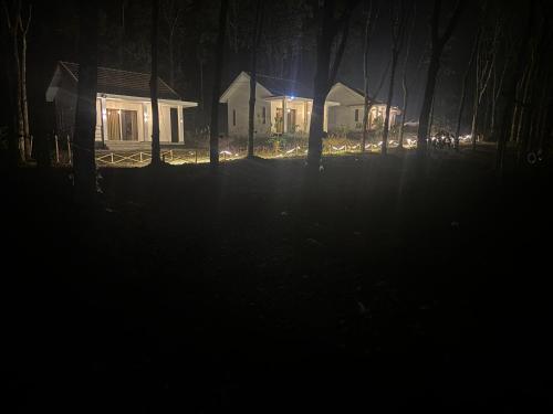 two houses at night with lights in the woods at Thoniyot Heritage villas in Kalpetta