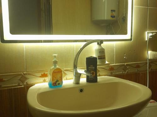 a bathroom sink with a bottle of soap and a mirror at Double room in Villa Narges New Cairo in Cairo