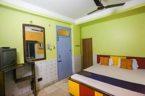 a room with a bed with a blue door and a tv at Hotel O Bideshini Hotel in Tarapith