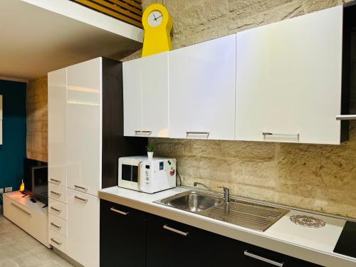 a kitchen with white cabinets and a sink and a microwave at Nel cuore di Giovinazzo in Giovinazzo