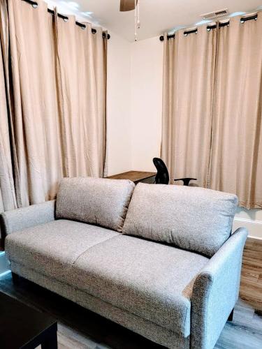 a couch sitting in a living room with curtains at Walk To Duke Campus! 1 Bedroom In Trinity Park! in Durham