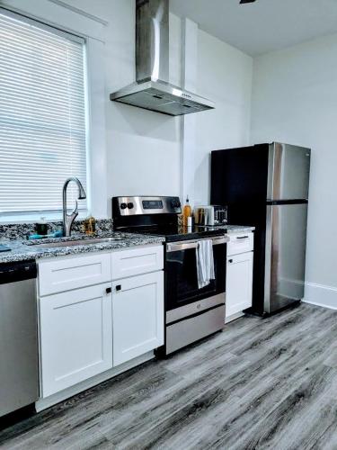 a kitchen with white cabinets and a black refrigerator at Walk To Duke Campus! 1 Bedroom In Trinity Park! in Durham