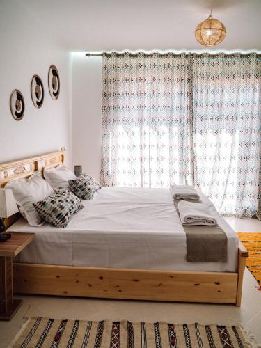 a bedroom with a large bed and a large window at Tamraght Bleu House in Tamraght Oufella
