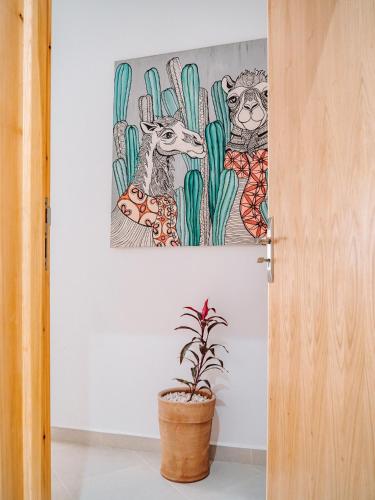 a painting of animals on the wall next to a plant at Tamraght Bleu House in Tamraght Oufella