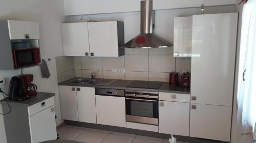 une cuisine avec des armoires blanches et un four à plaques de cuisson dans l'établissement CHALET AU CALME à GERARDMER, à Gérardmer