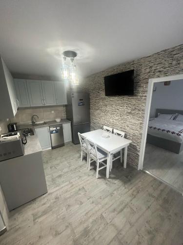 a kitchen with a white table and a room with a bed at Casa Berbec 3 Studio in Dealul Viei