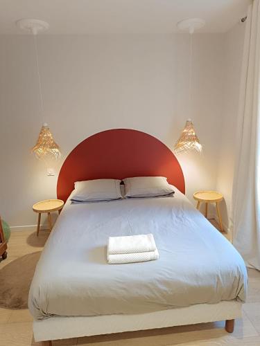 une chambre avec un grand lit avec une tête de lit rouge dans l'établissement La Nichée appartement 2 chambres, à Trévoux