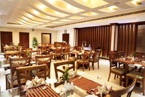 a restaurant with tables and chairs in a room at Athirappilly Residency Chalakudy in Kizhake Chālakudi
