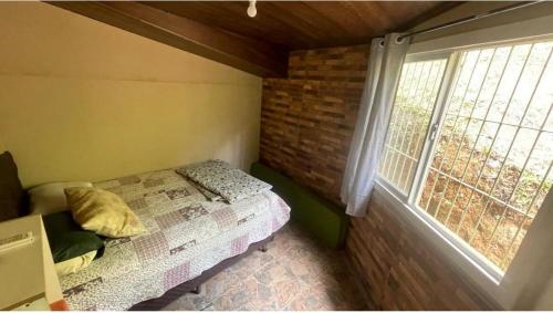 a small bedroom with a bed and a window at Casa de campo in Itapema