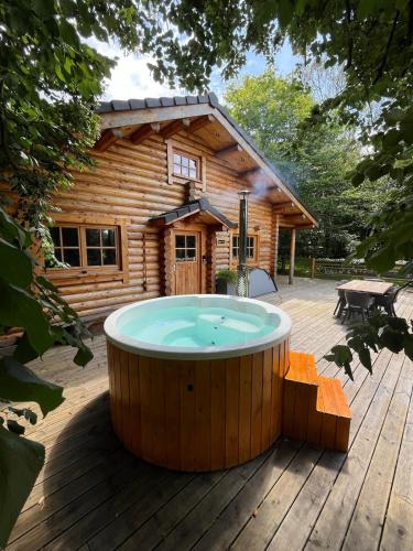 bañera de hidromasaje en una terraza frente a una cabaña de madera en Le chalet Nord, en Verviers