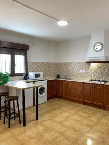 a kitchen with wooden cabinets and a table with a microwave at Casa Teresa in Alcalá del Júcar