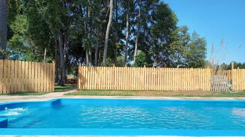 a blue swimming pool in front of a wooden fence at Cabaña con tinaja más hidromasaje in Temuco