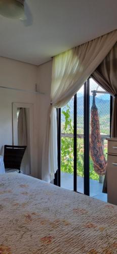 a bedroom with a bed and a large window at Suite completa Ilhabela - com varanda e vista panorâmica in Ilhabela