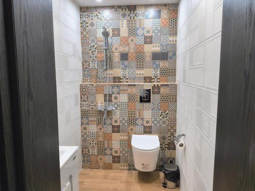 a bathroom with a toilet and a tiled wall at St Sava Legendary House in Veliko Tŭrnovo
