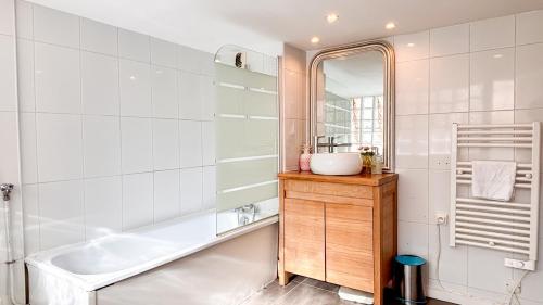 une salle de bain avec une baignoire, un lavabo et un miroir dans l'établissement Appartement XVIIIème centre historique, à Bordeaux