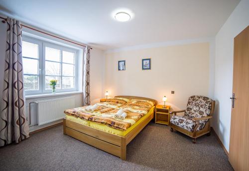 a bedroom with a bed and a chair and a window at Pension Jana in Český Krumlov