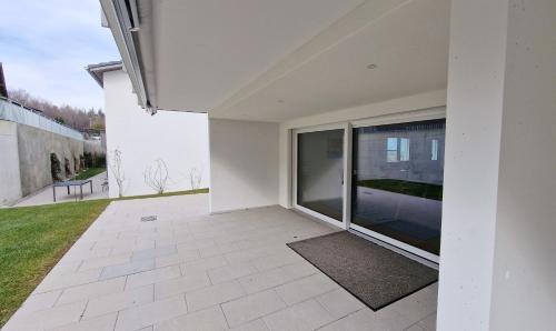 a white house with a patio with a large window at Mountainside Homestay in Spiez by Menbergs Harmony Homestay in Spiez