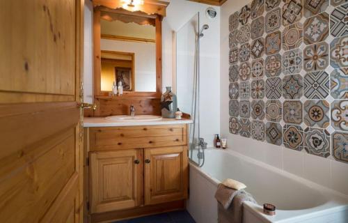 une salle de bain avec une baignoire et un lavabo et une baignoire dans l'établissement lesetoilesdelaplagne chalet 16 au pied piste a belle plagne, à La Plagne Tarentaise