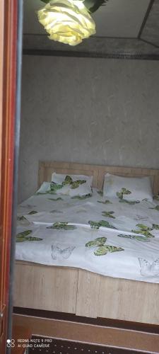a bed with white sheets and green designs on it at Farida Bonu Sam in Samarkand