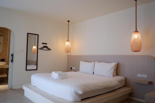 a bedroom with a white bed with two pendant lights at Sunvada Beach Rayong in Rayong