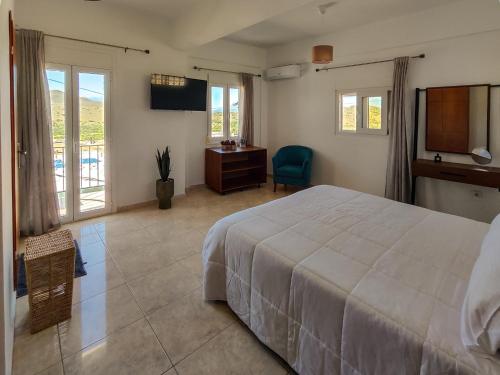 Un dormitorio con una gran cama blanca y un escritorio. en Maisonette in Kavousi with Mountain View, en Kavoúsion