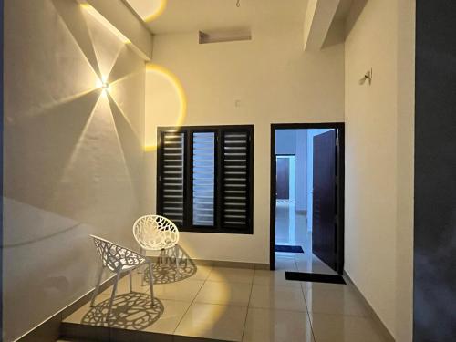 a dining room with two chairs and a window at Sunrise Boutique Villa in Kozhikode