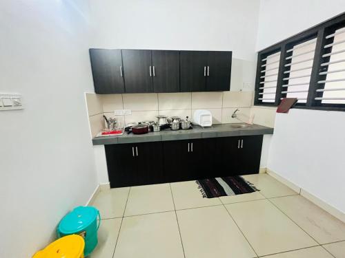 a kitchen with black cabinets and a tiled floor at Sunrise Boutique Villa in Kozhikode