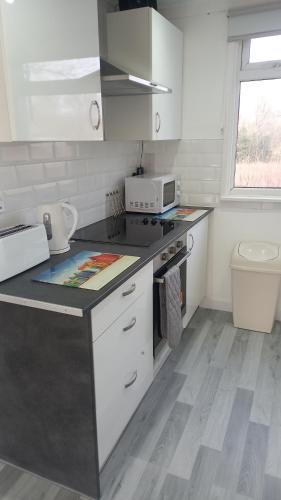 a kitchen with white cabinets and a counter top at Chalet Bleu in Sandown
