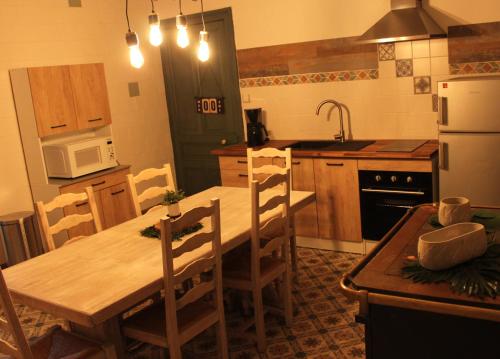 une cuisine avec une table en bois avec des chaises et un réfrigérateur dans l'établissement O' Domaine des Folies, à Grand-Fayt