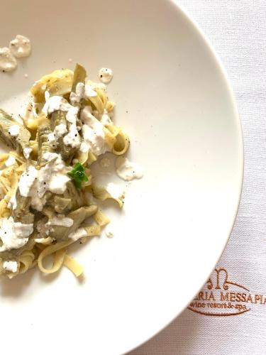 a white plate of food with pasta on a table at Masseria Messapia Wine Resort & Spa Salento in Mesagne