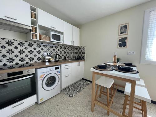 une cuisine avec une machine à laver et une table dans l'établissement bel appartement proche plage, au Lavandou