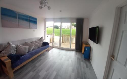 a living room with a blue couch and a television at Chalet Bleu in Sandown