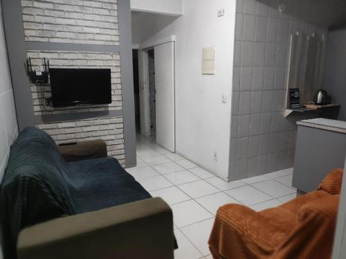 a living room with a couch and a tv at Havaí SV in São Vicente