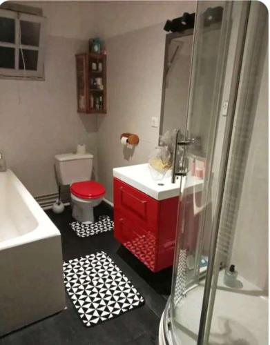 La salle de bains est pourvue d'un lavabo rouge et de toilettes. dans l'établissement Chambre d'hôte avec salle de bain cosy au coeur du marais de Longeville-sur-mer, à Longeville-sur-Mer