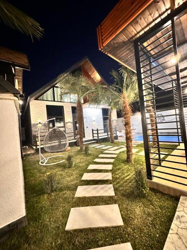 a garden with palm trees and a pathway at Qafqaz Retro Bungalow HOT POOL in Gabala