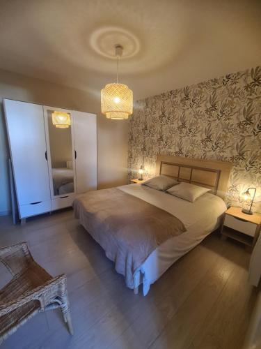 une chambre avec un grand lit et un lustre dans l'établissement Gîte les pieds dans l'eau, face au port de plaisance, classé 3 étoiles, à Fécamp